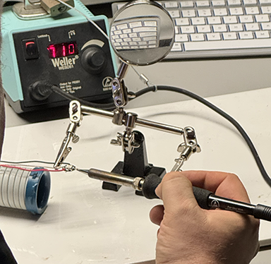 Using the gator clip to hold the wires you are soldering as it is more steady then shaly hands and the material is very hold and could cause a serious burn so its best to keep hand out of the way. Positioning the iron and waiting a couple of seconds to head the metal. Then adding some solder to the joint.      